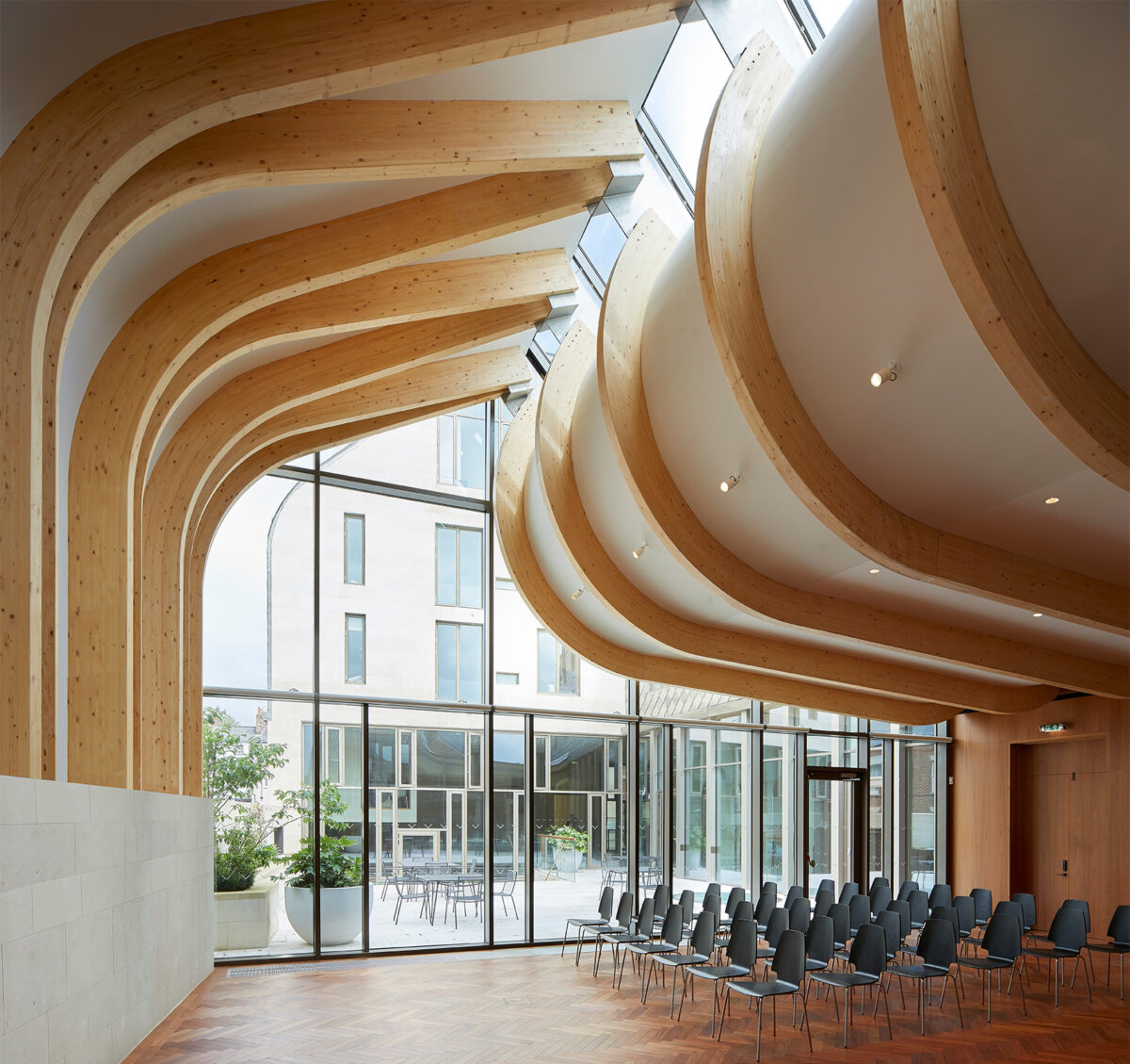 A photograph of the Cohen Quad at Exeter College, designed by Alison Brooks Architects, showcasing the firm's expertise in adaptive reuse and conservation-focused heritage architecture. The image highlights the project's sensitive integration of new and historic elements. Below the image, the text states that Alison Brooks Architects has won the Best Medium Firm prize for the Architizer A+ Awards, which is recognized in over 80 countries.